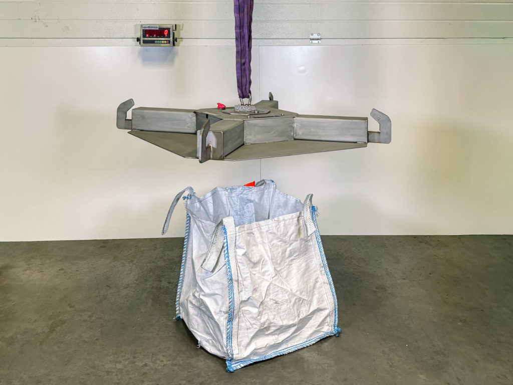 Image of full bespoke weighing solution showing a bag hanging underneath a stainless steel suspended weighing cross and the digital display in the background