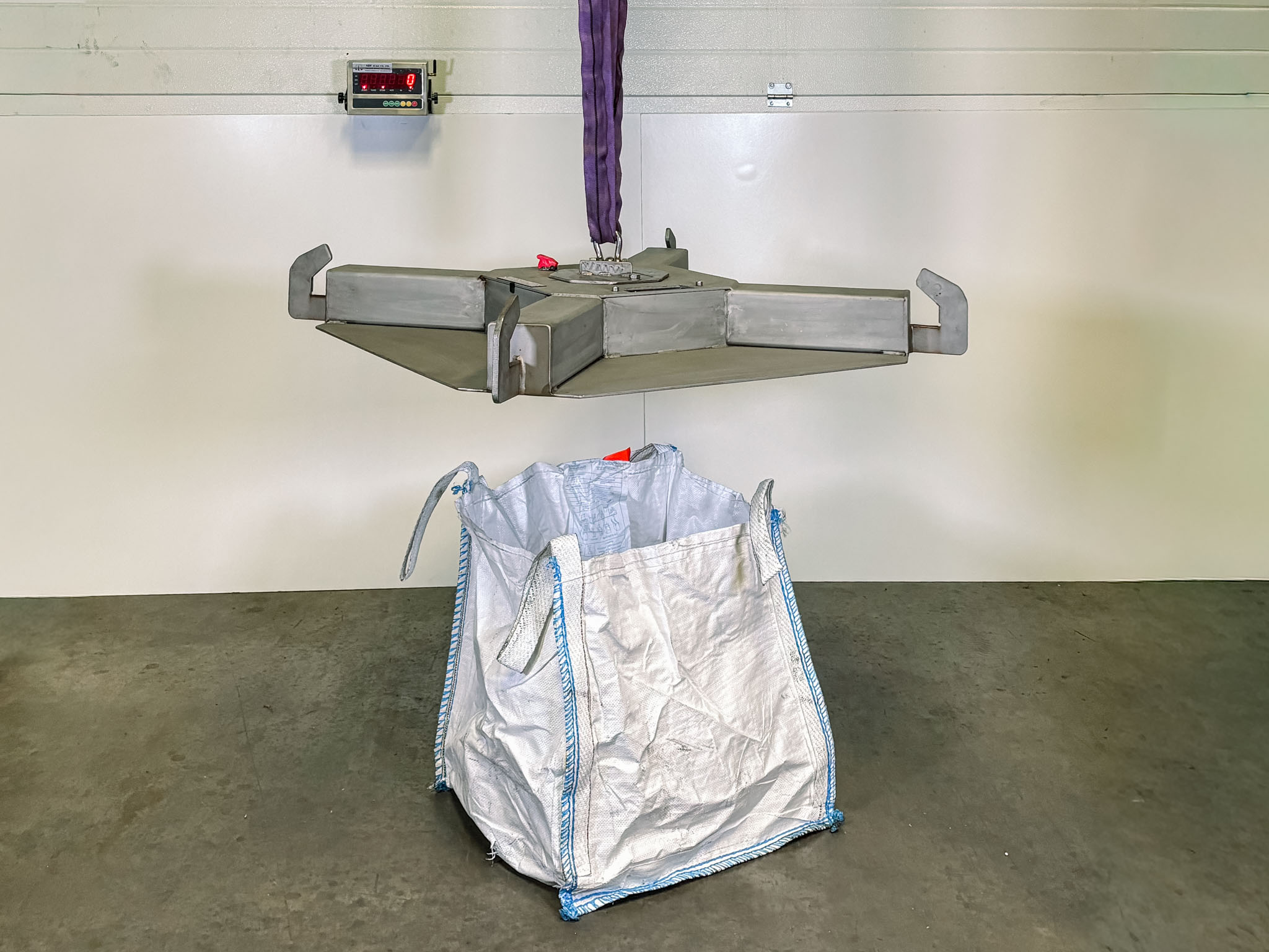 Image of full bespoke weighing solution showing a bag hanging underneath a stainless steel suspended weighing cross and the digital display in the background
